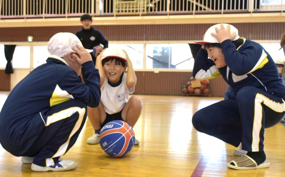 「防災バスケ」で身を守る姿勢を取る児童=高萩市有明町