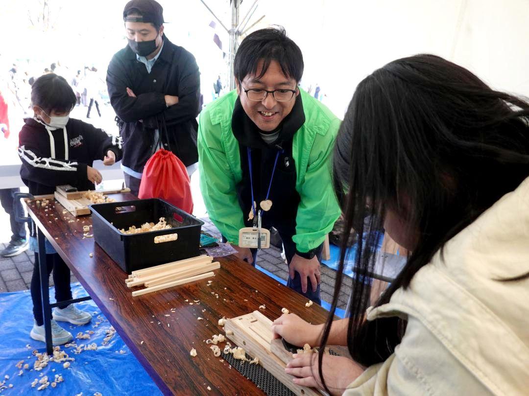 スタッフの助言を受けながら、かんなを使って箸作りを体験する来場者(手前)=ひたちなか市佐和