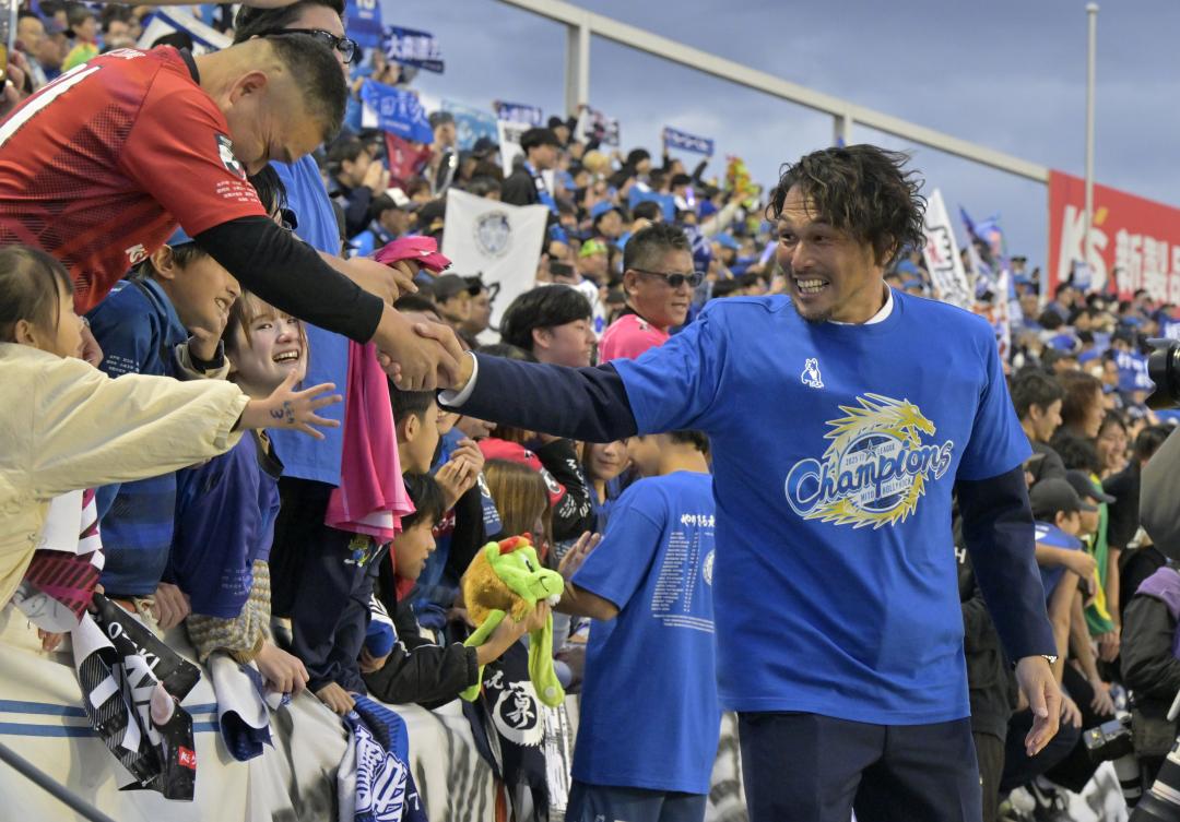 水戸のJ1昇格が決まり、サポーターと握手を交わす本間幸司CRO(右)=ケーズデンキスタジアム水戸