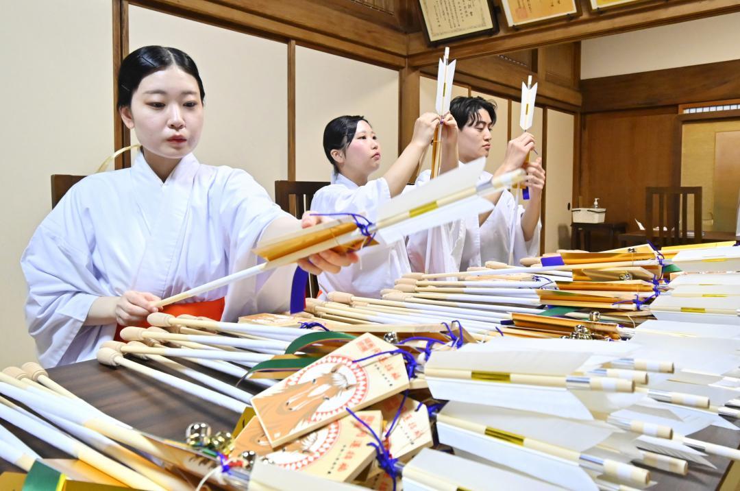 来年のえとのうまが描かれた絵馬を破魔矢に結ぶ巫女ら=鹿嶋市宮中