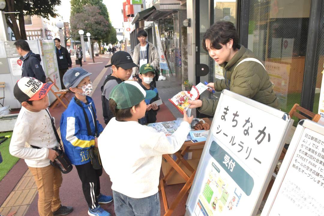 空き店舗の前で街歩きイベントに参加する子どもたち=日立市幸町
