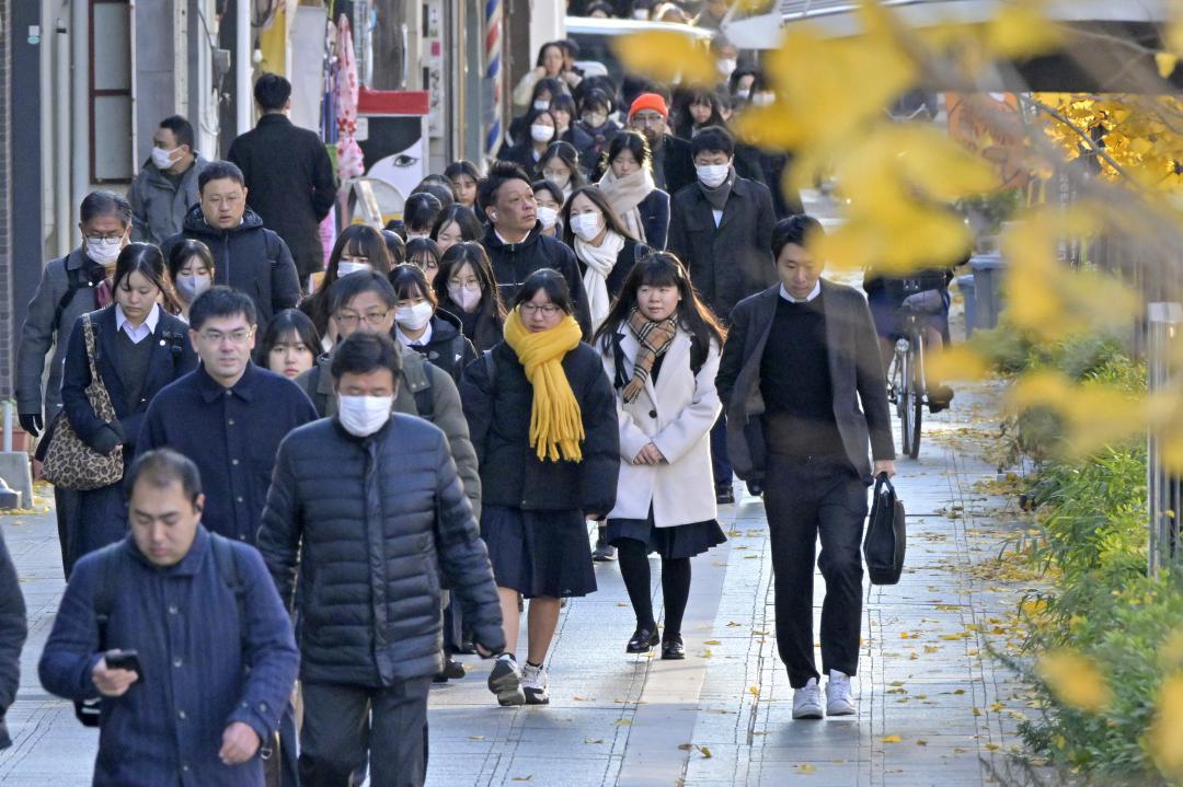 イチョウの落葉が進む中、コートやマフラーを着用して通勤通学する人たち=5日朝、水戸市三の丸