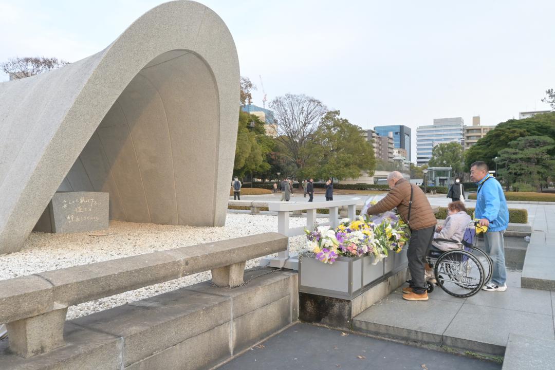 広島平和都市記念碑に献花する希望号の参加者たち=広島市
