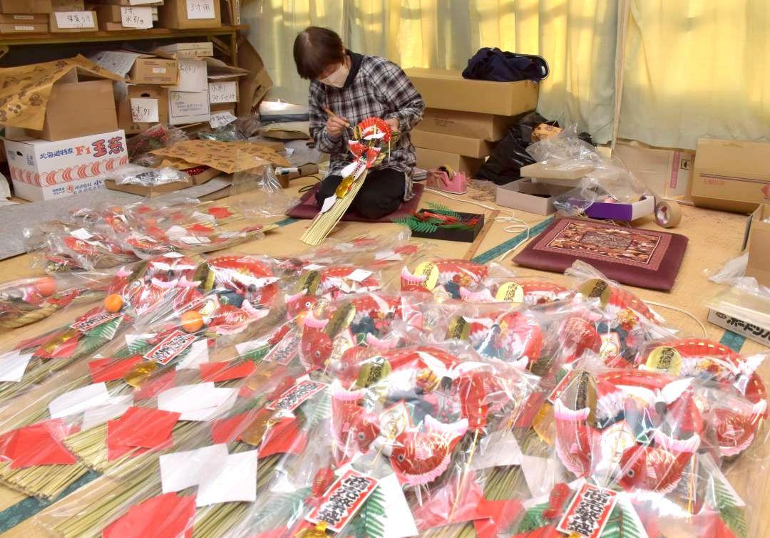 紅白の扇など縁起物をしめ縄に飾り付けるスタッフ=常陸太田市大中町