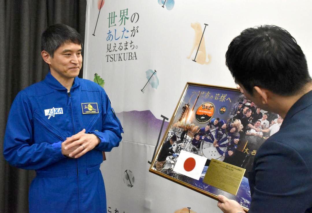 写真のパネルについて説明する宇宙飛行士の大西卓哉さん=つくば市役所