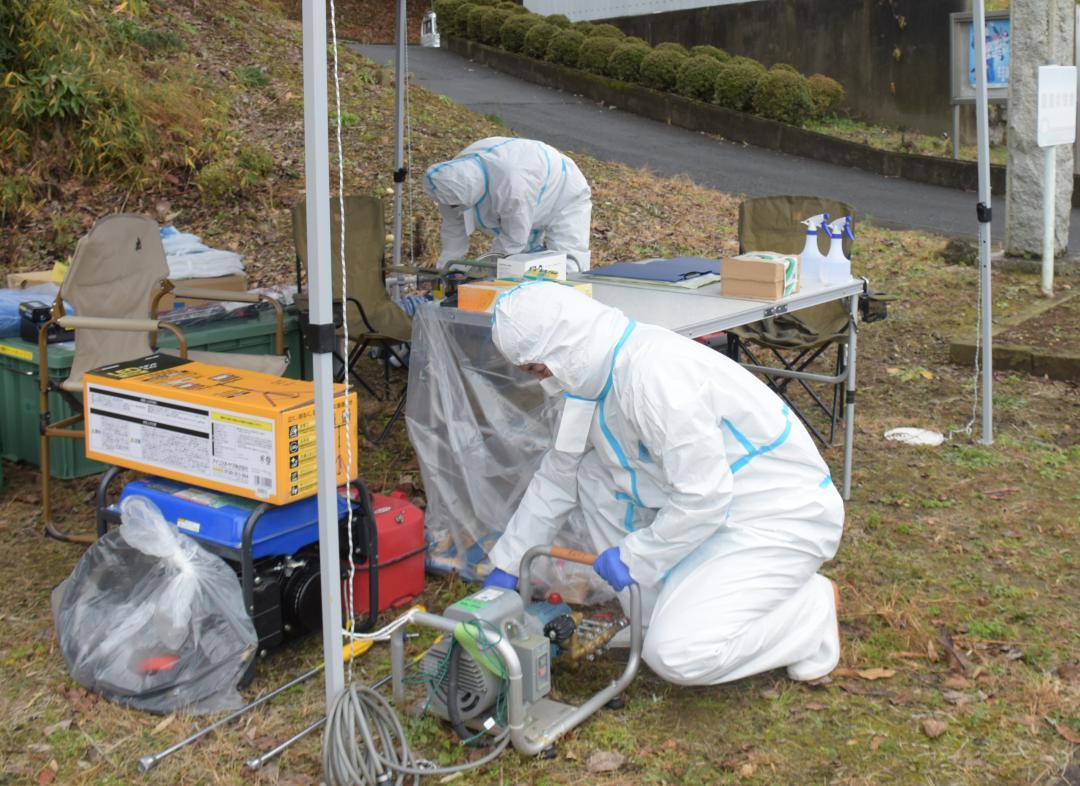 飯富市民センター前に設置された車の消毒ポイントで動力噴霧器を用意する作業員=水戸市飯富町