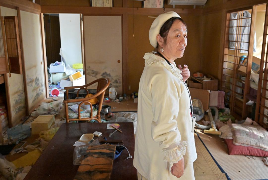 帰還困難区域にある自宅に一時帰宅し、家財などが散乱した部屋で立ち尽くす守家文子さん=福島県双葉町
