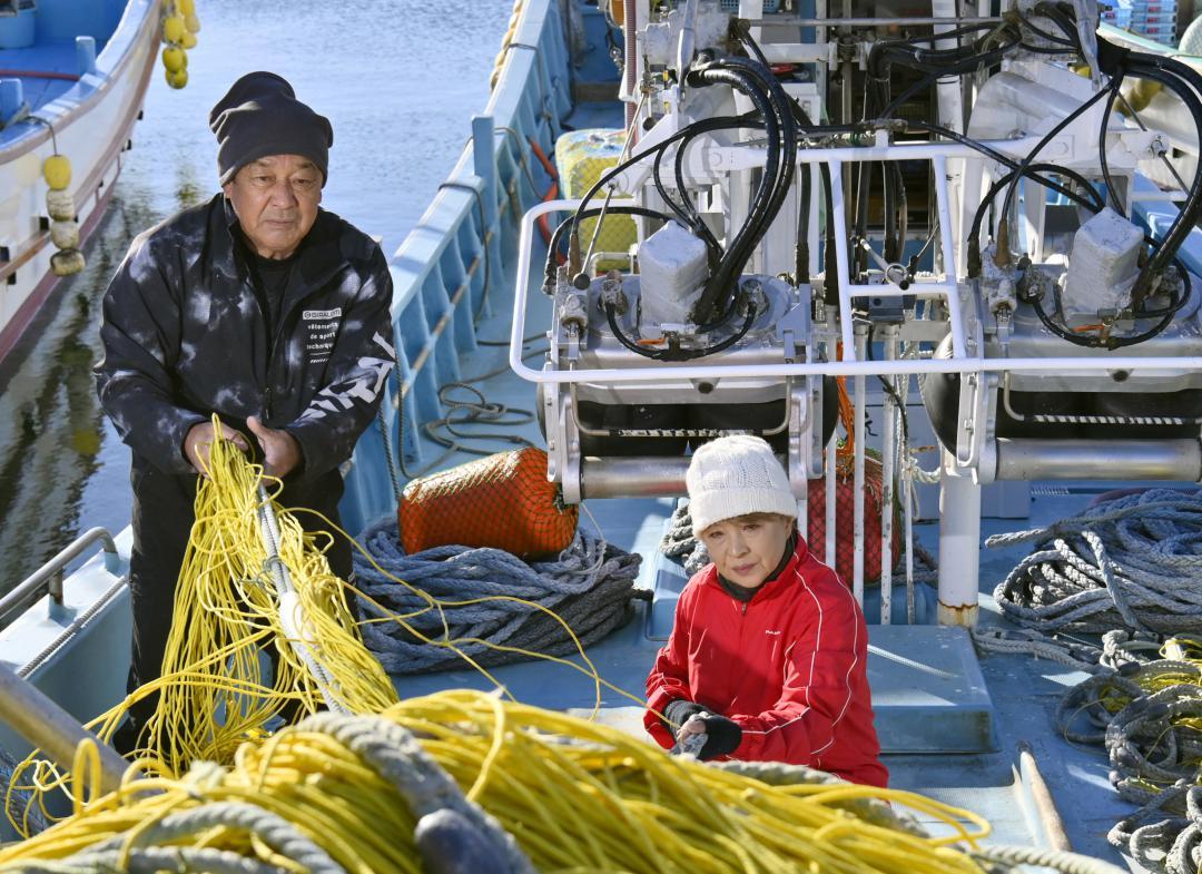 次の漁に向けて修繕した網を船に積み込む山形隆さん、美紀さん夫妻=北茨城市大津町
