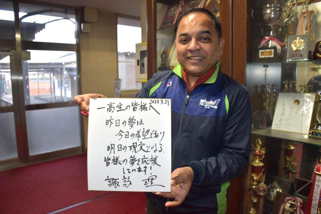 諏訪理さんが書いた色紙を持つプラニク・ヨゲンドラ土浦一高校長=土浦市真鍋