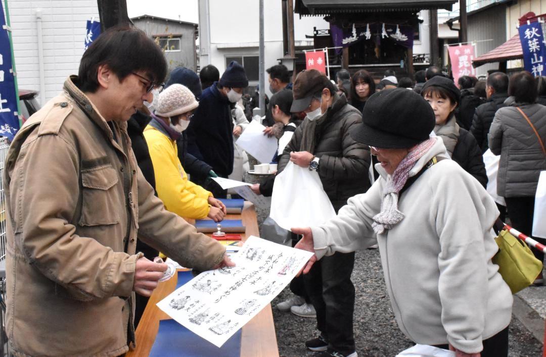 神社境内で専用の台紙にスタンプを押してもらう七福神めぐりの参加者ら=古河市本町