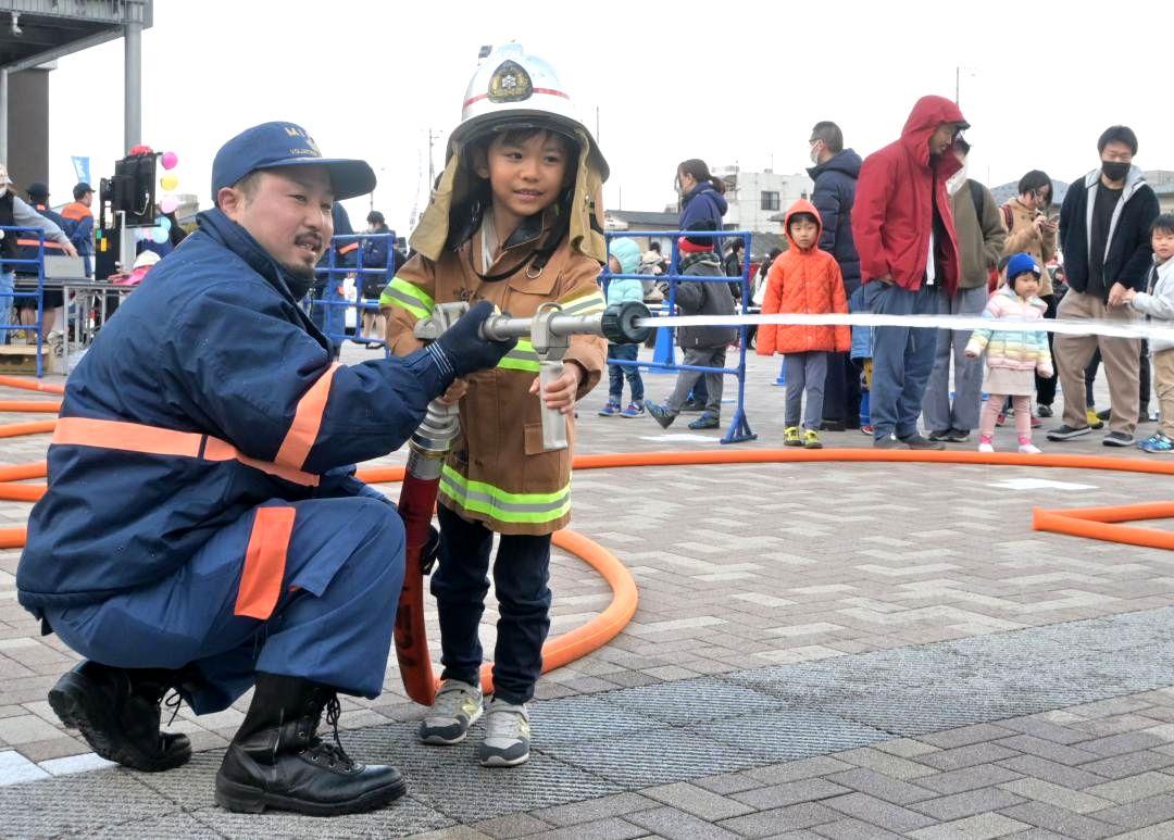 防火服姿で放水する子ども=水戸市緑町
