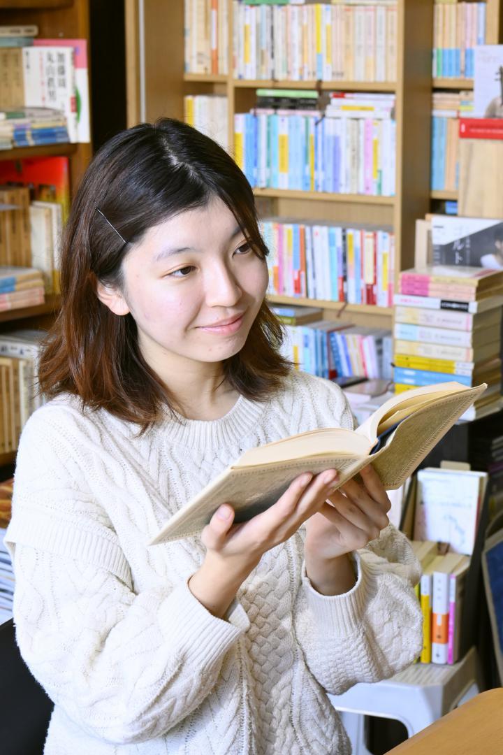 行きつけの私設図書館で、本を読みながら作品づくりの着想を得る高塚しいさん=水戸市袴塚