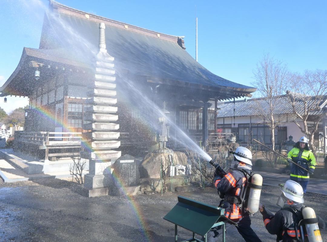 本堂に放水する消防隊員ら=那珂市額田北郷