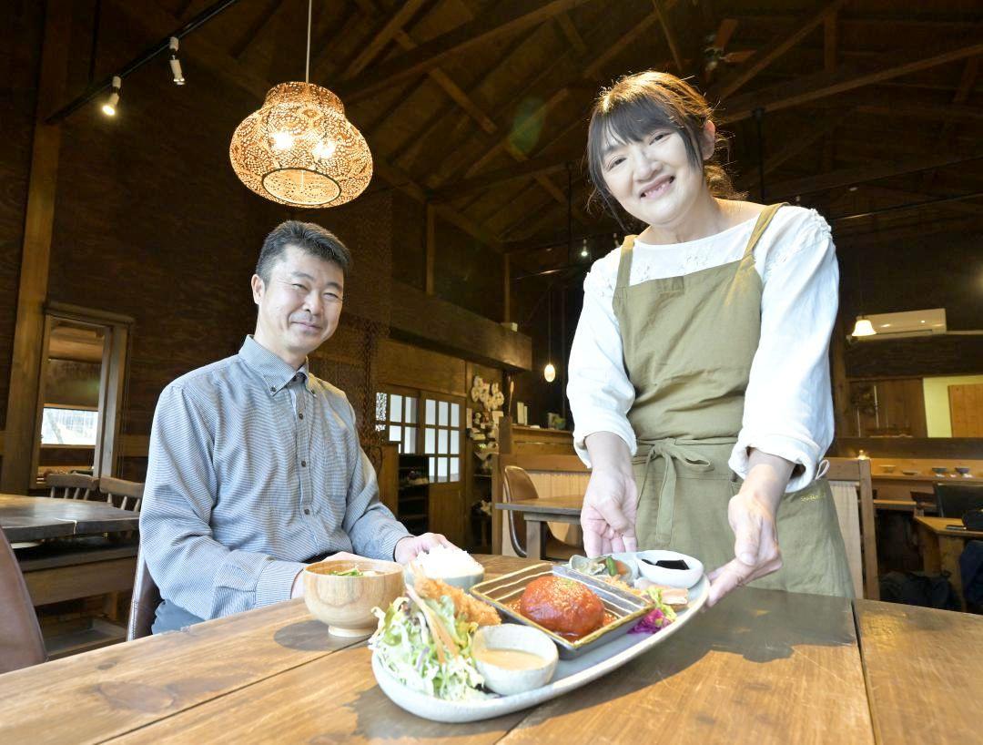 看板のプレートランチを手に笑顔を見せる高松博さんと紀子さん(左から)=笠間市笠間