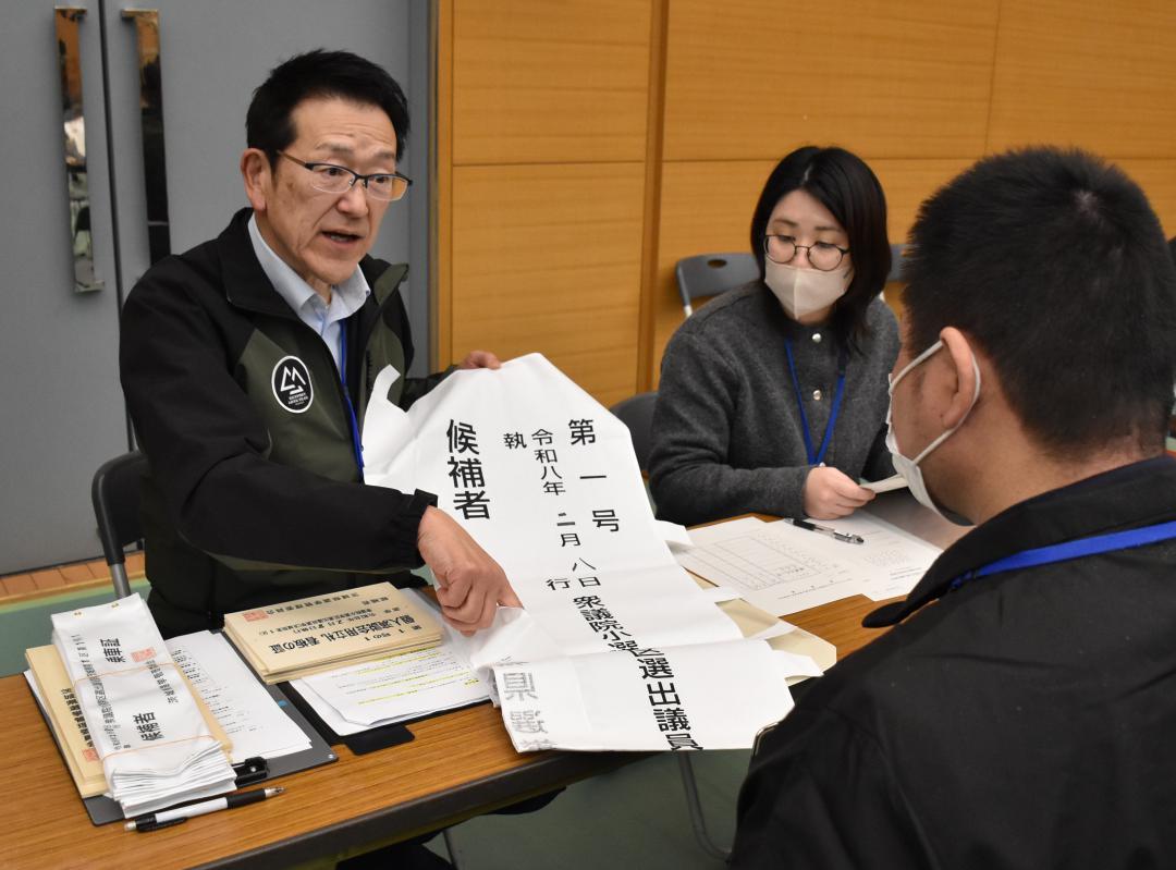 選挙の「七つ道具」を候補者役(手前)に説明する県選管の担当者=県庁