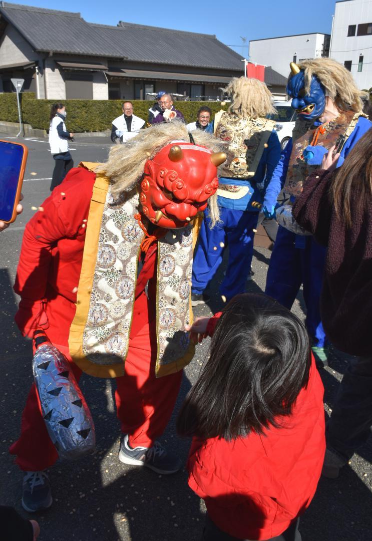 赤鬼に豆を投げる女の子(手前)=潮来市日の出