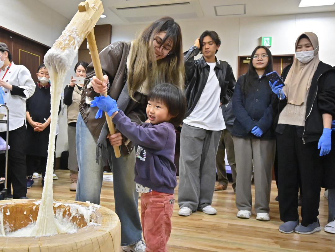 国際交流イベントで、子どもと一緒に餅をつく留学生の女性=水戸市開江町