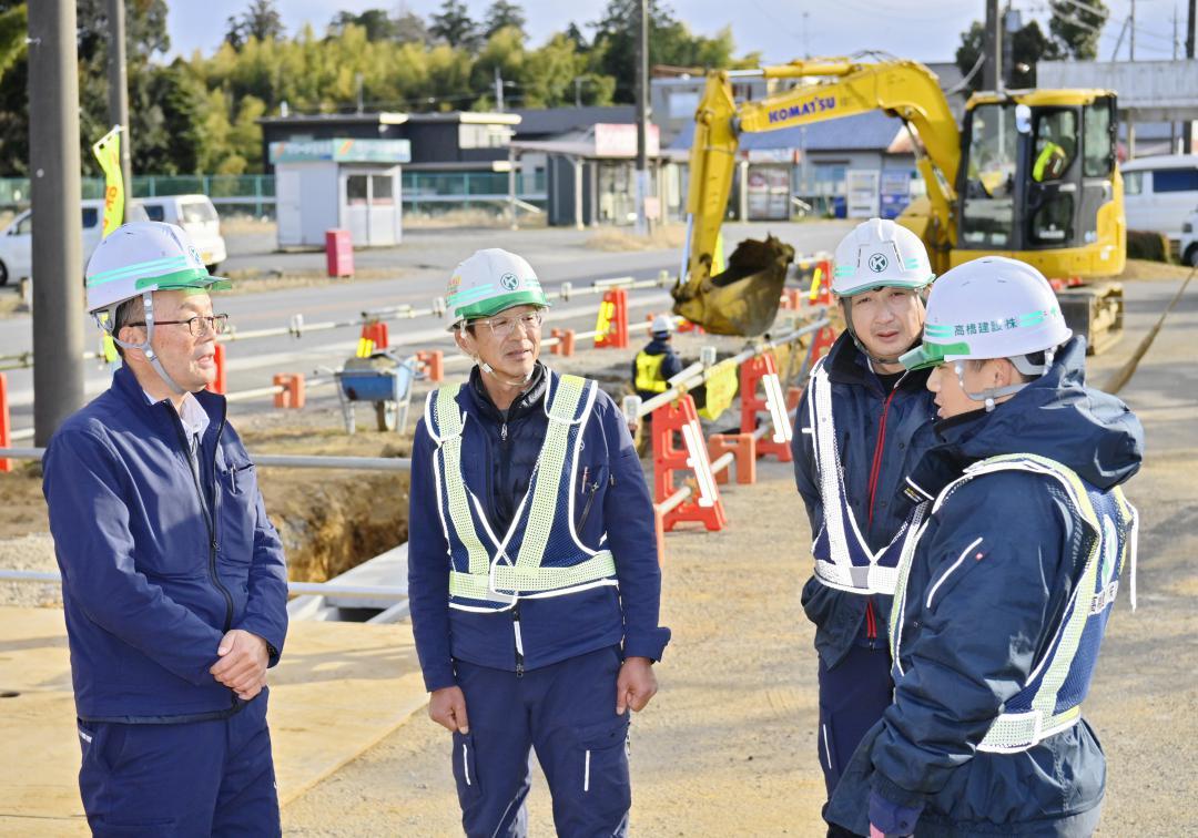 道路工事の現場で、進展状況を確認する高橋建設の高橋修一社長(左)=行方市山田