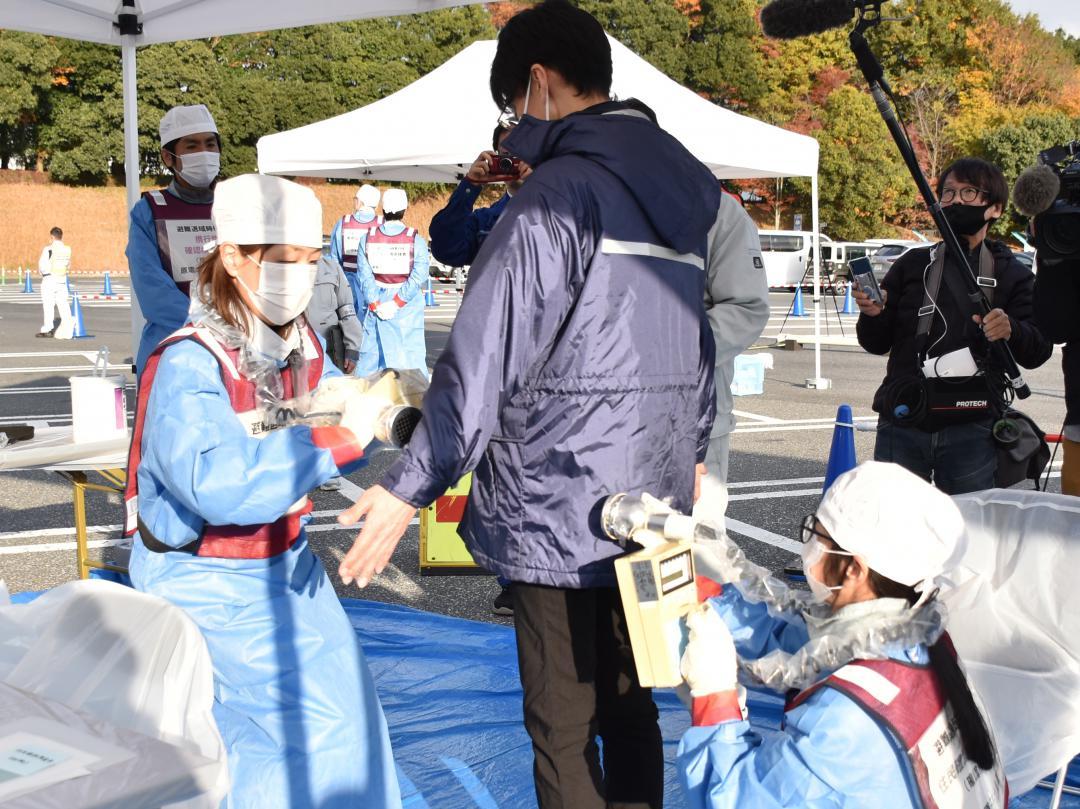 スクリーニング検査の訓練で、サーベイメーターを使って放射性物質による汚染箇所がないか調べる検査担当者=2025年11月20日、笠間市長兎路