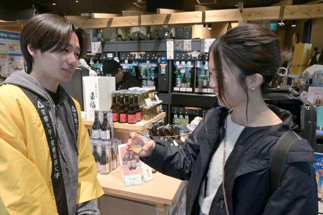 ビールを試飲し「フルーティーで飲みやすい」と話す駅利用者(右)=水戸市宮町