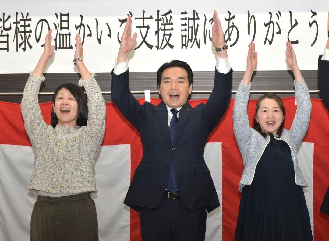 当選確実の一報を受け支持者らと万歳する浅野哲氏=日立市幸町