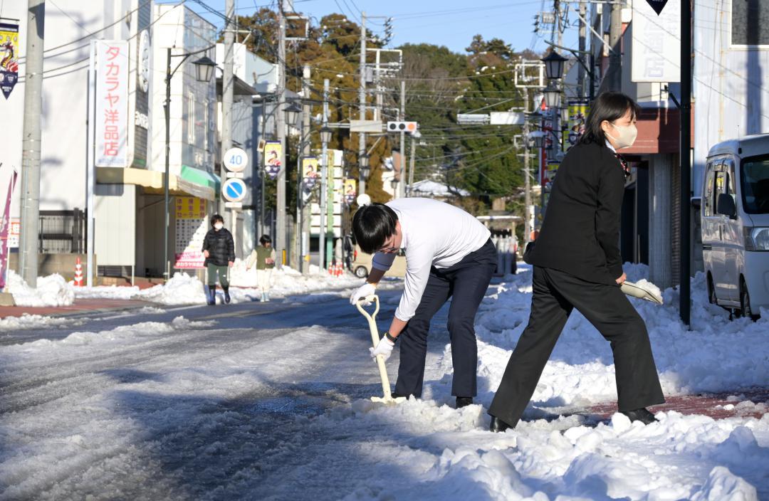 歩道の除雪をする人たち=9日午後3時44分、鹿嶋市宮中