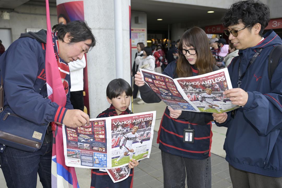 「ヴァモス・アントラーズ」を手に取る鹿島サポーターら=メルカリスタジアム