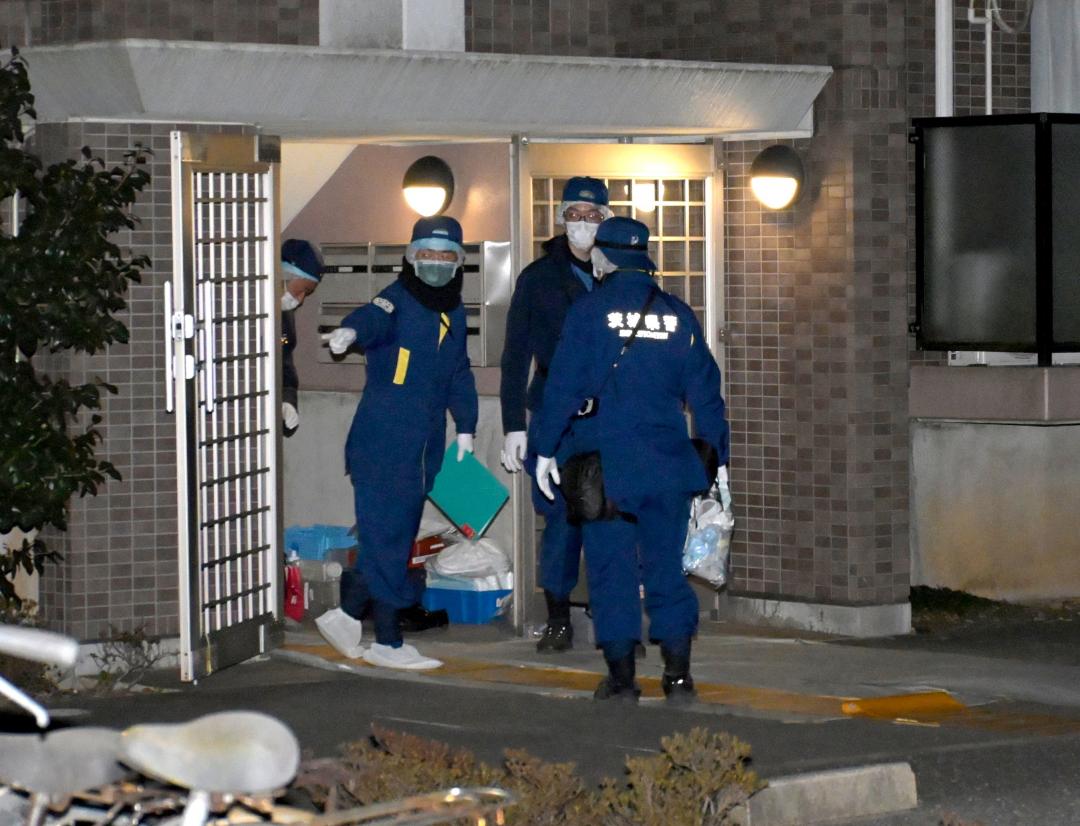 男性が殺されたアパートの出入り口に立つ警察官ら=19日午後6時50分、潮来市延方西