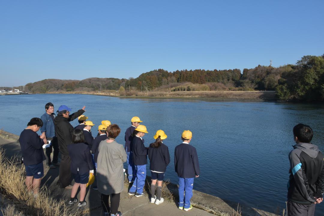 町生涯学習課文化財係長の蓼沼香未由さんから説明を聞きながら、織姫塚を見学する大洗小たんけんクラブの子どもたち=大洗町磯浜町