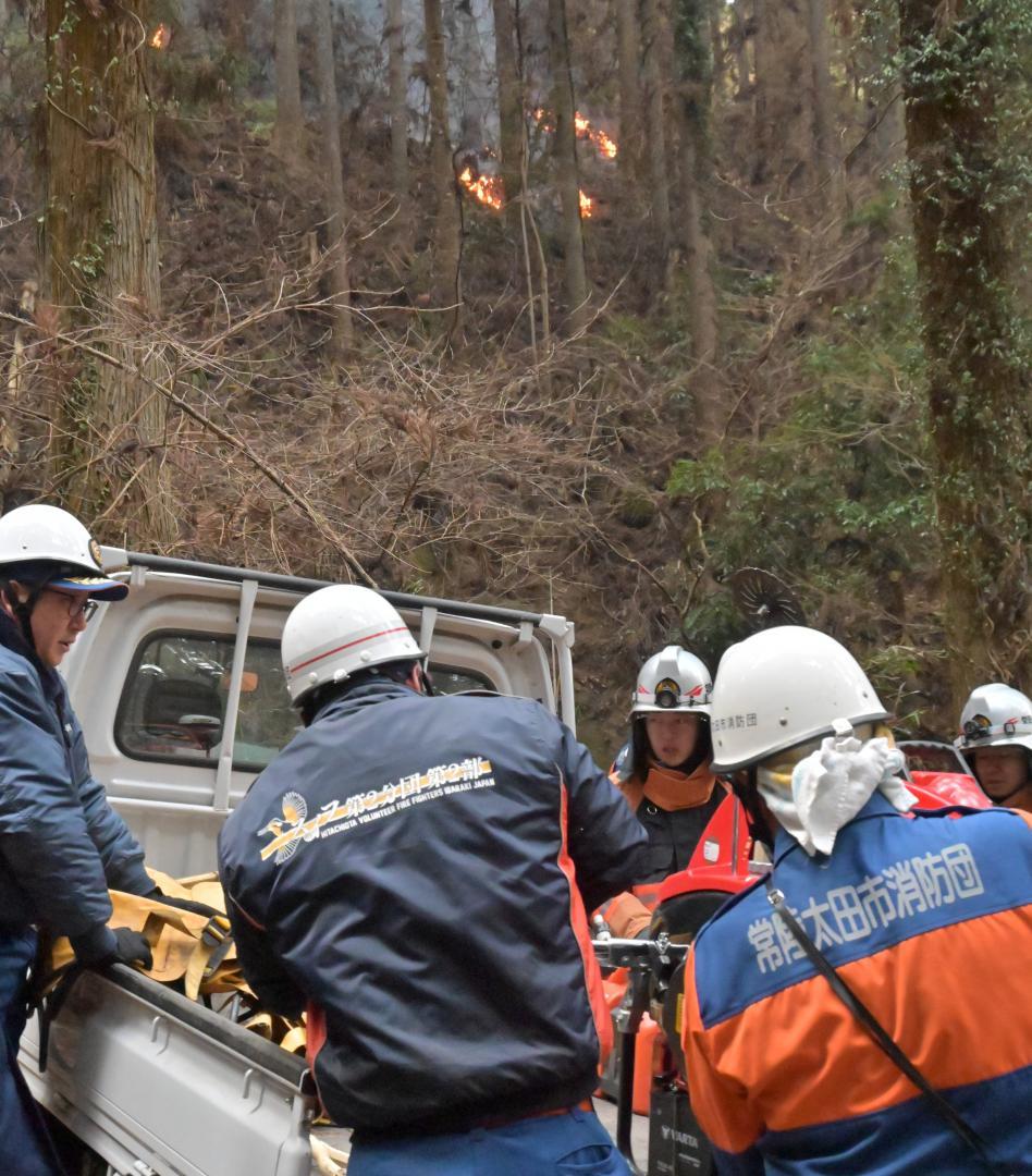 山林火災の現場で活動する消防団員ら=21日午後3時半ごろ、常陸太田市内