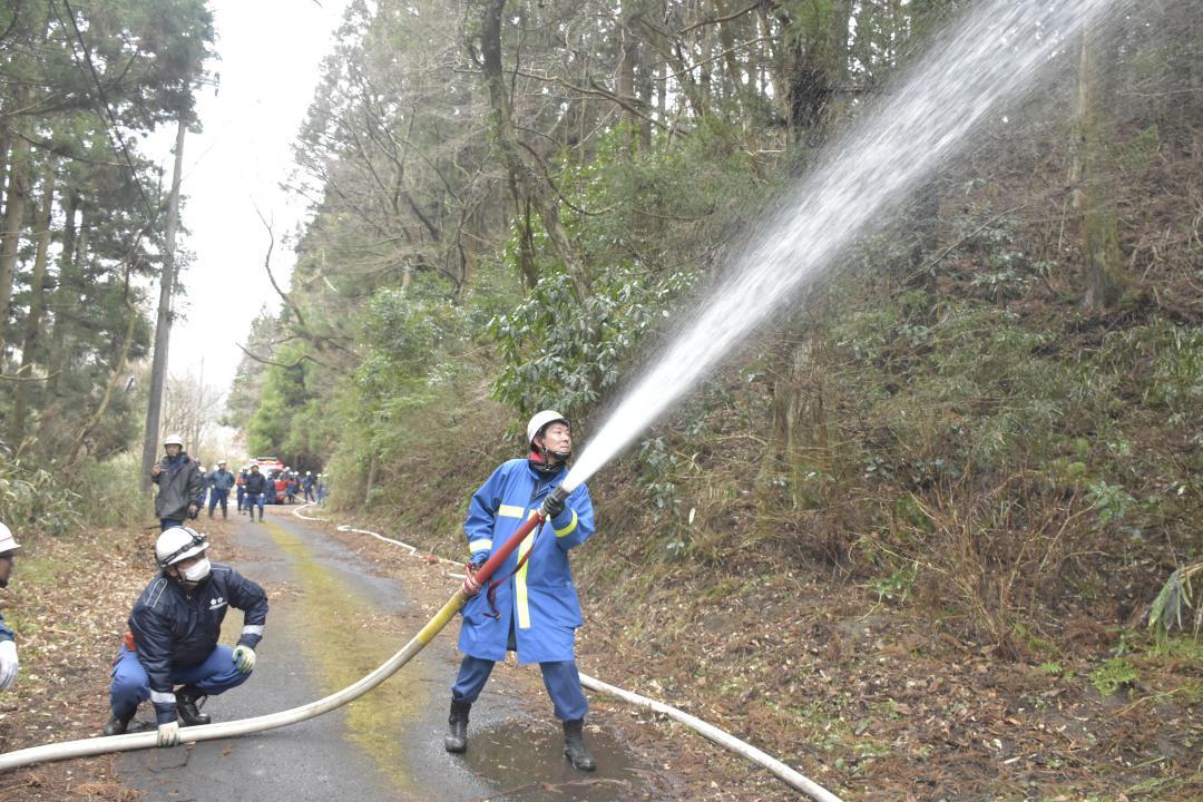 飛び火を警戒し、麓で予防散水を行う消防団員=22日午後1時50分ごろ、常陸太田市小菅町