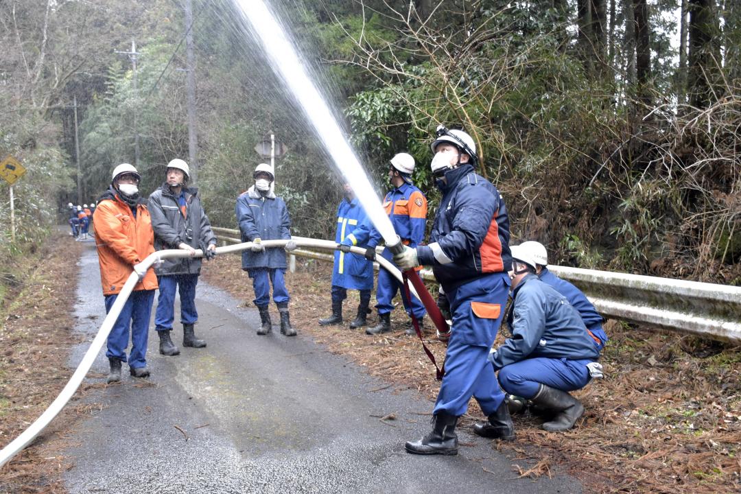 飛び火を警戒し予防散水を行う消防団員=22日午後1時50分ごろ、常陸太田市小菅町