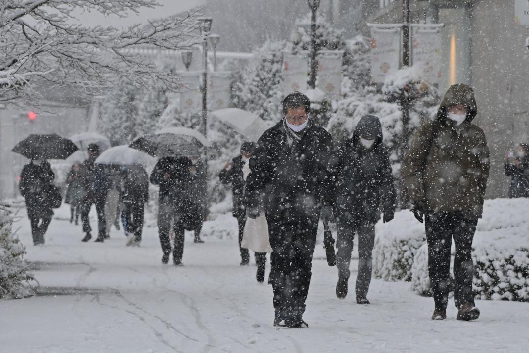 降りしきる雪の中を歩く人たち(資料写真)