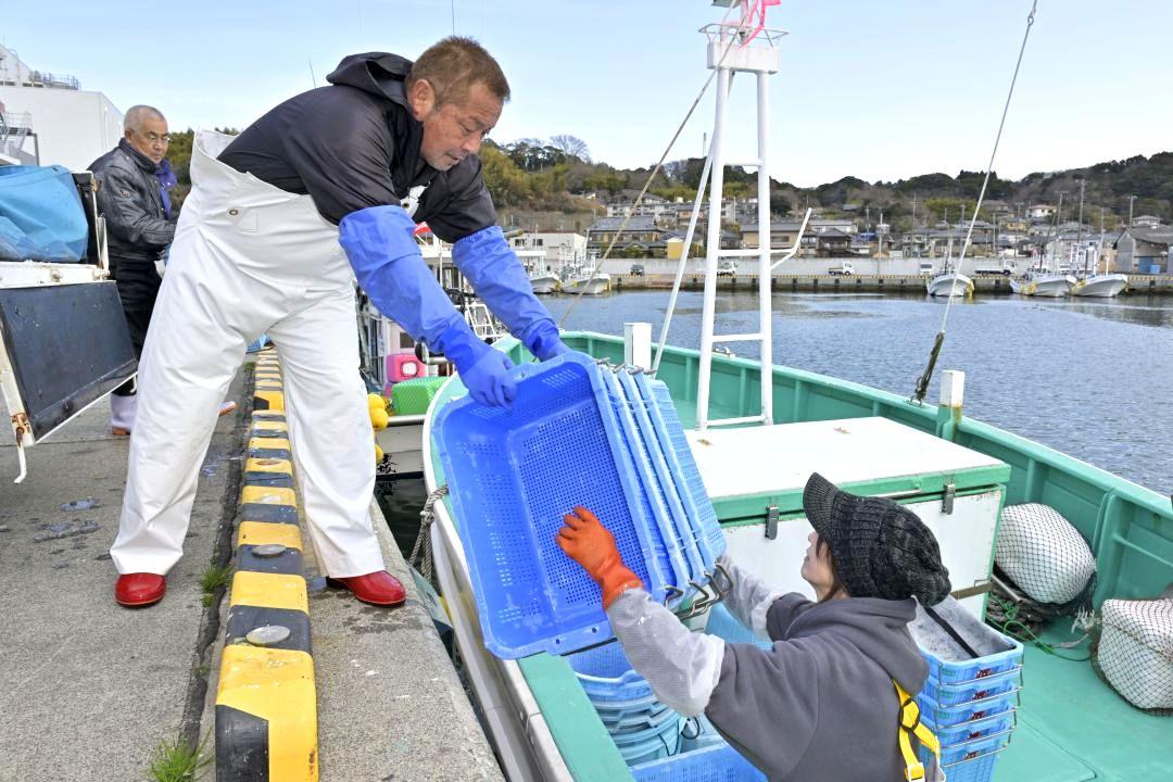 漁から戻り、水揚げした魚を入れる籠を再び船に積み込む伊藤治さん(左)と妻の理恵さん=北茨城市大津町の大津漁港