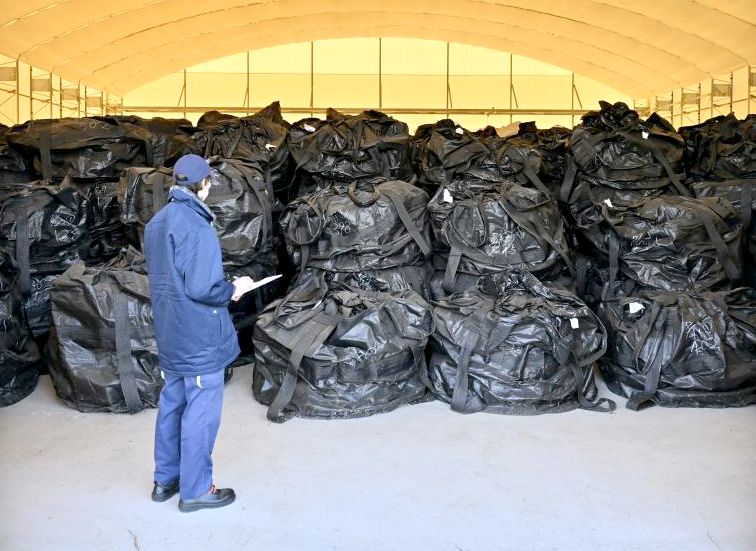 倉庫に保管する指定廃棄物の状態を確認する自治体職員=県央地域