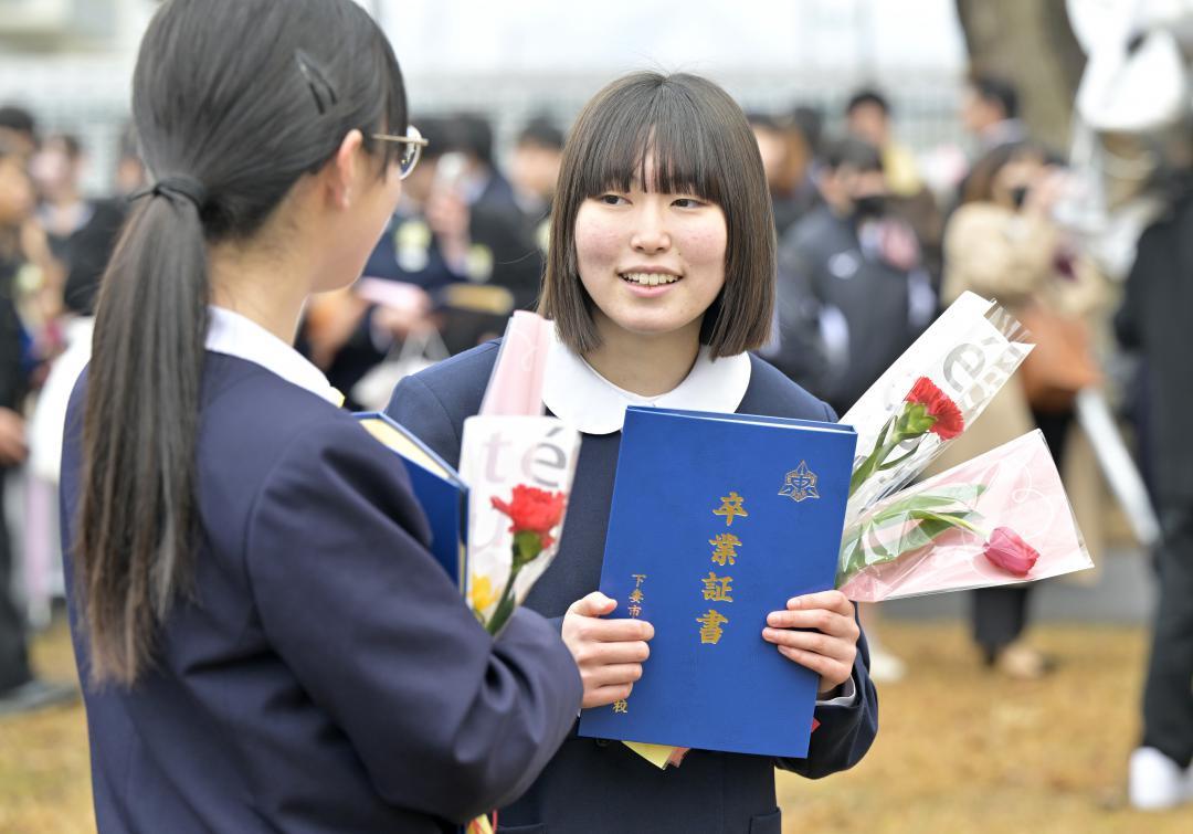 卒業式を終え、友人と笑顔で話す大塚摩耶さん(右)=下妻市長塚乙