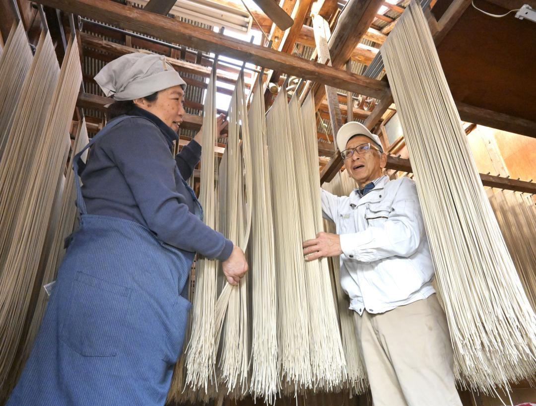 工場内でそばを干す間中健一郎さんと正美さん(右から)。温度や湿度に気を配りながら半日～20時間ほど乾燥させる=坂東市長須