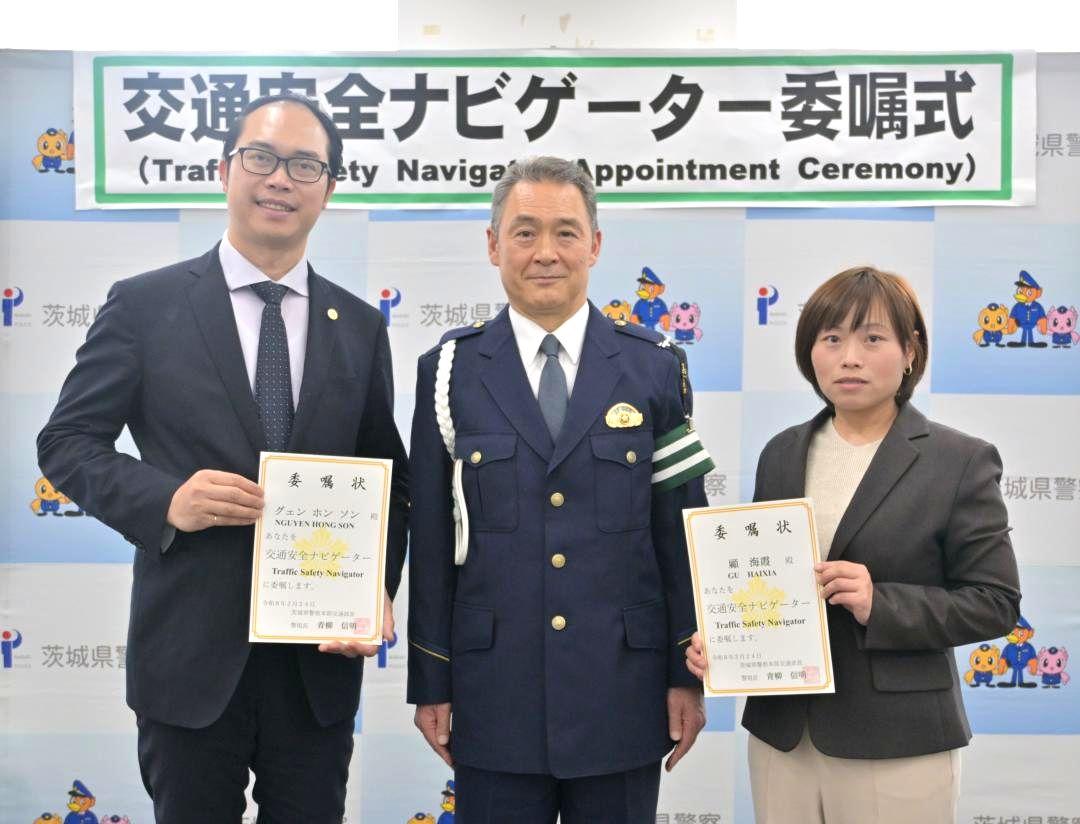 青柳信明県警交通部長(中央)から「交通安全ナビゲーター」に委嘱された顧海霞さん(右)とグエン・ホン・ソンさん=県警本部