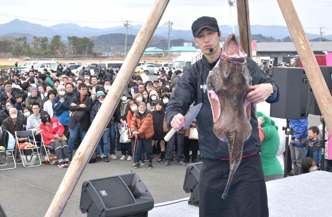 アンコウのつるし切りと、見守る来場者ら=北茨城市関南町(下)来場者に自慢の「どぶ汁」を提供する事業者