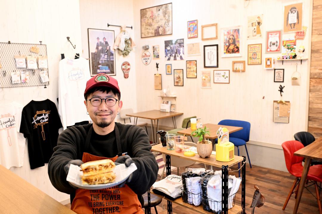 人気のホットサンドを持ち笑顔を見せる角田将樹さん=東海村舟石川駅西