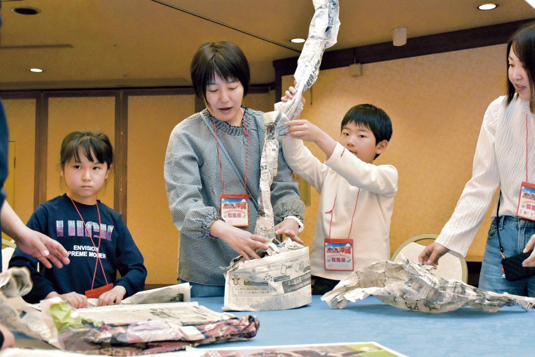 レクリエーションで新聞タワー作りに挑戦する親子=沖縄県恩納村(画像の一部を加工しています)