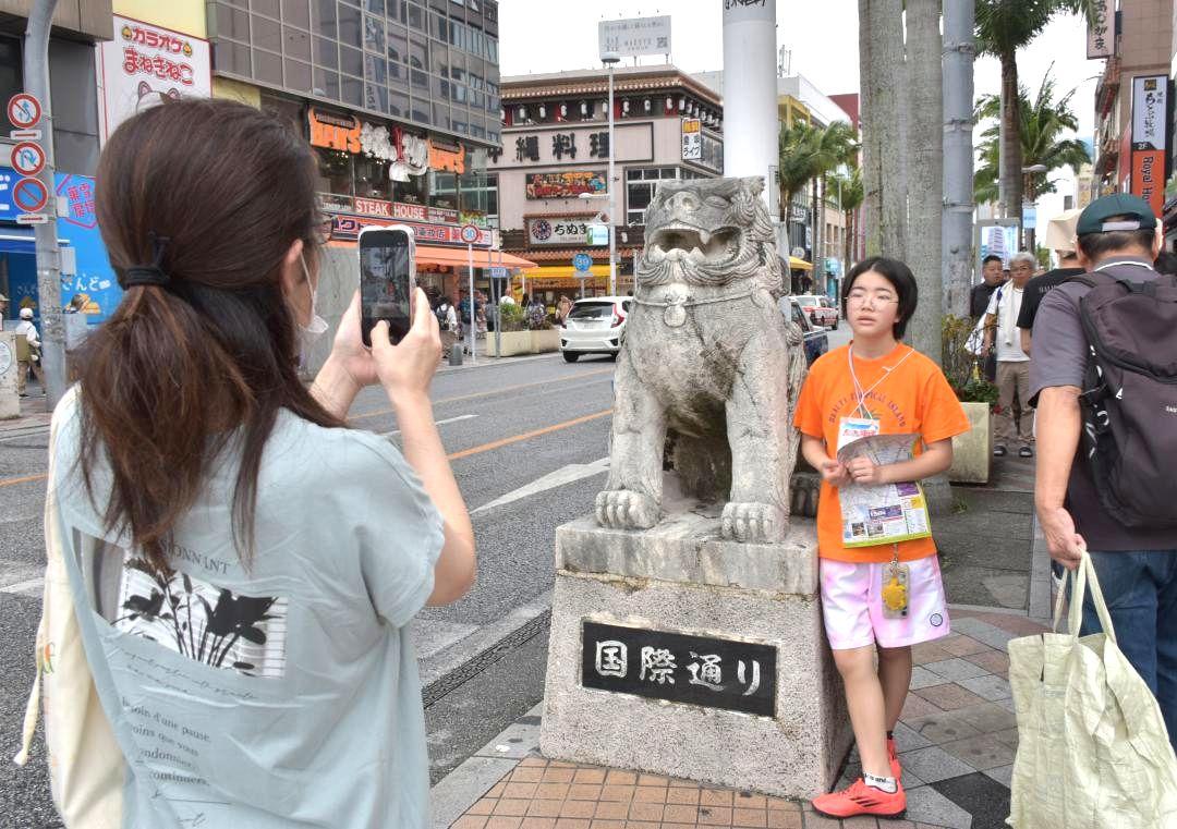 飲食店や土産物店が立ち並ぶ国際通りで記念撮影する親子=5日午前、那覇市