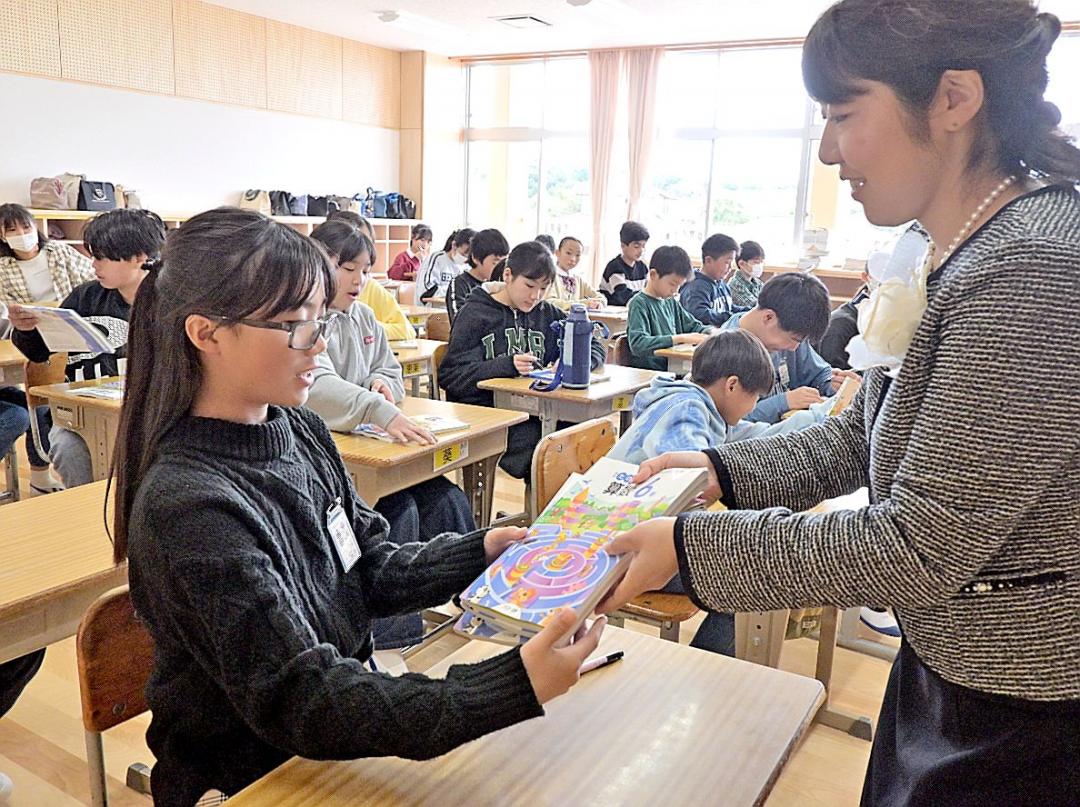 新校舎の教室で担任教諭から新しい教科書が配られた=鉾田市玉田