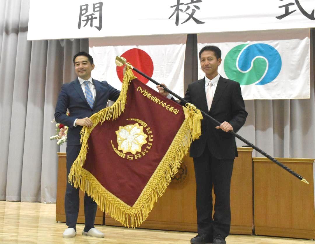 開校したさくら小学校の校旗を持つ五十嵐立青つくば市長(左)と岡野知樹校長=同市春風台