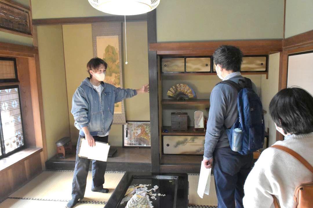 旧佐藤呉服店を開放したツアーで来場者に説明する茨城大生(左)=日立市白銀町