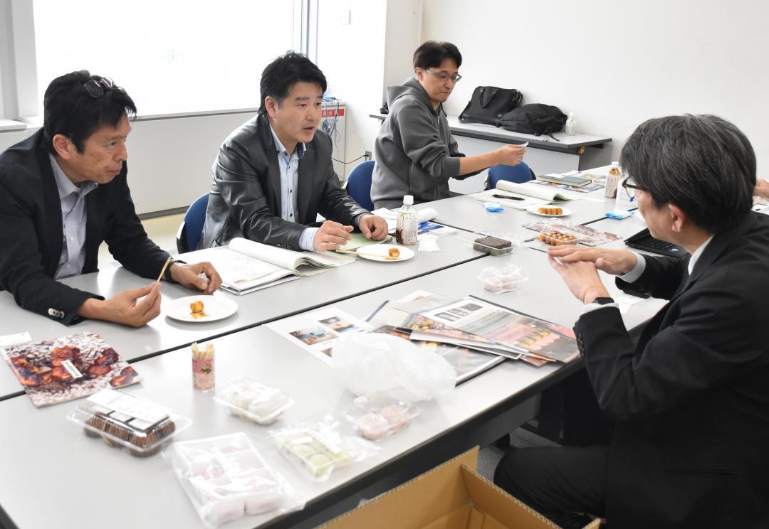 森永牛乳配給の担当者(右)に商品の売りなどを聞くOsaka　Marketplaceの竹田一浩COO(奥中央)=県庁